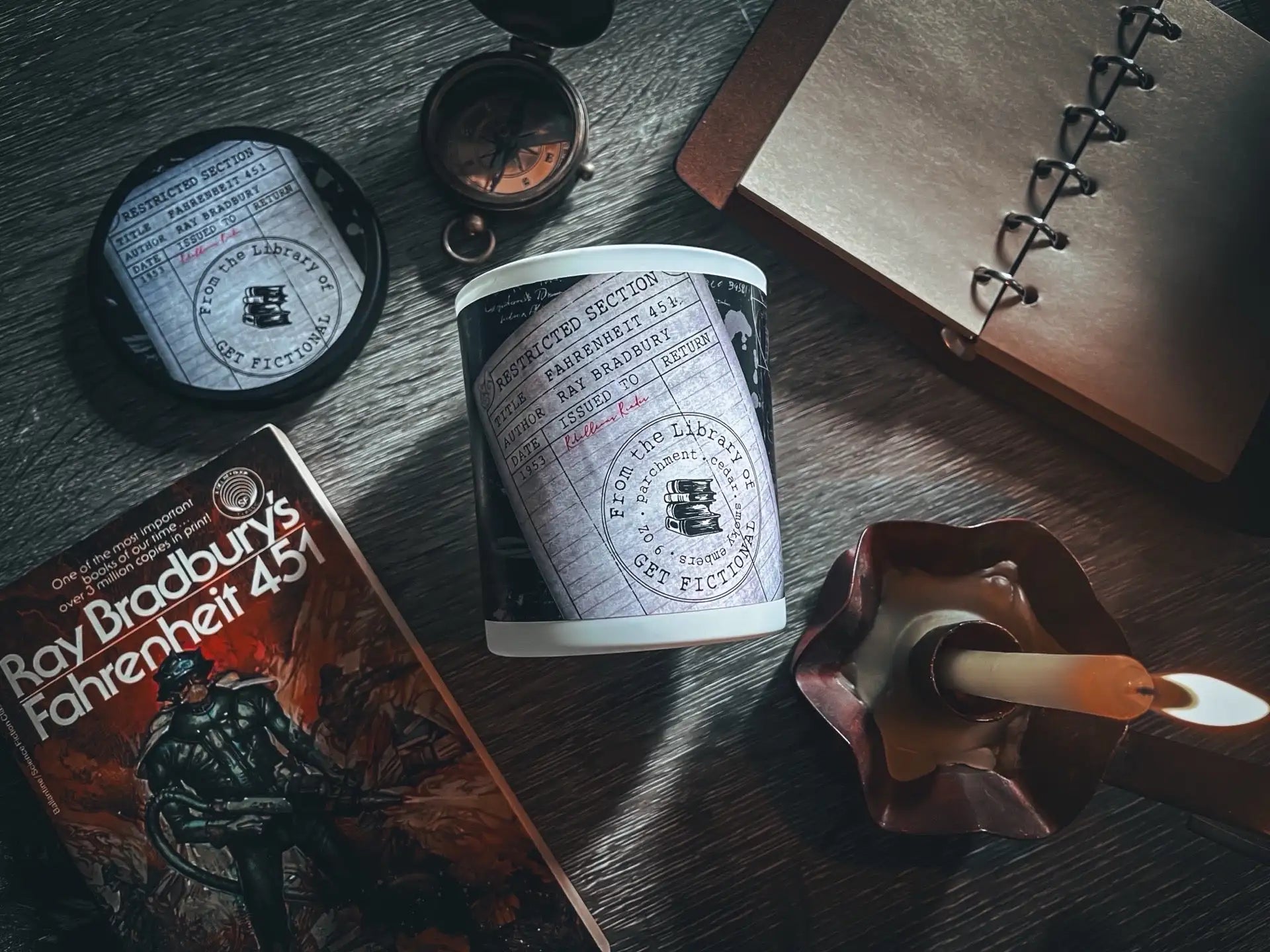 White candle with black label and red wax drip, cylindrical shape.