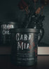 A black candle in a dark gray tin with a decorative label.