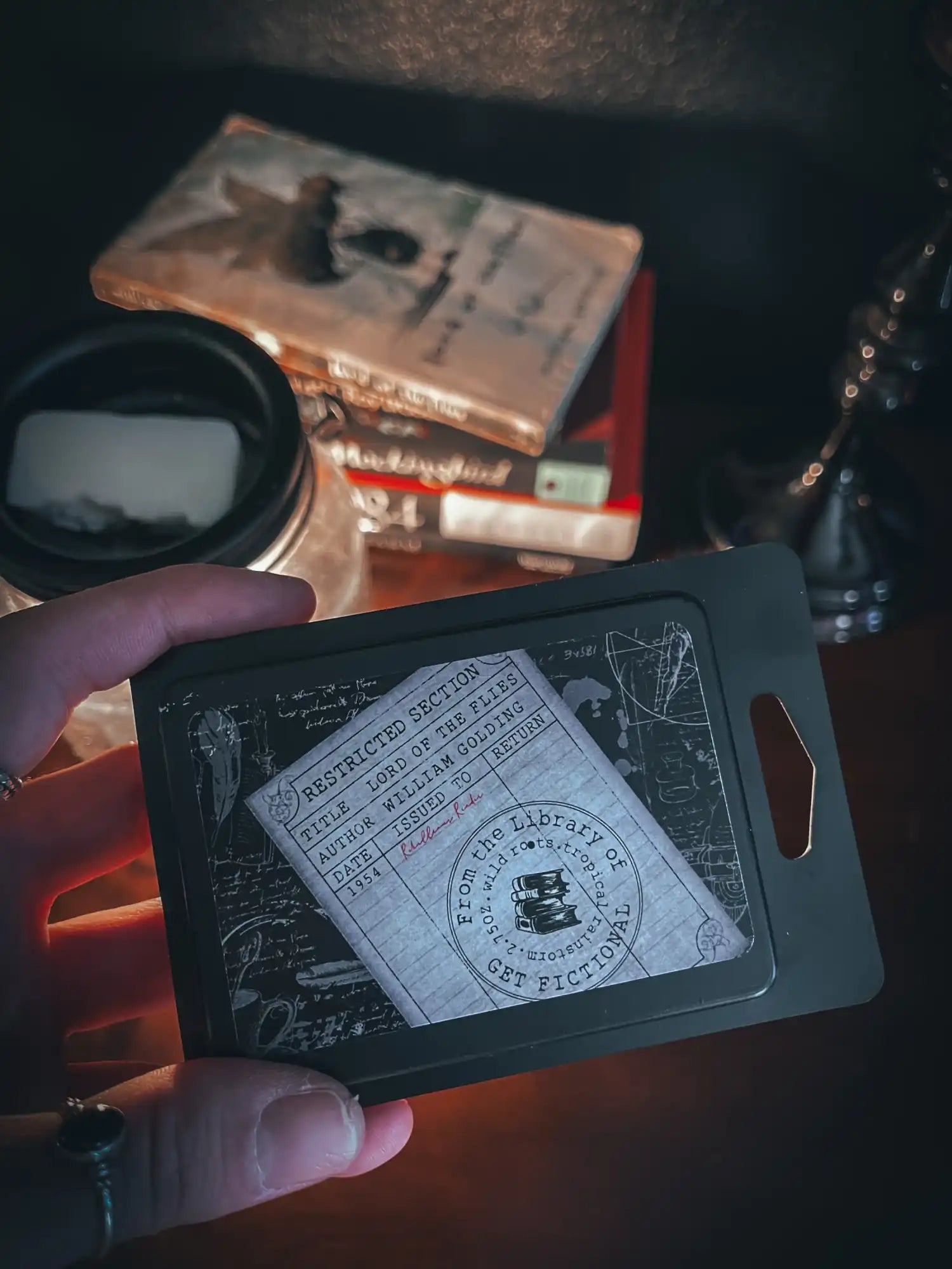 A black rectangular card holder with a vintage-style library card slip inside.