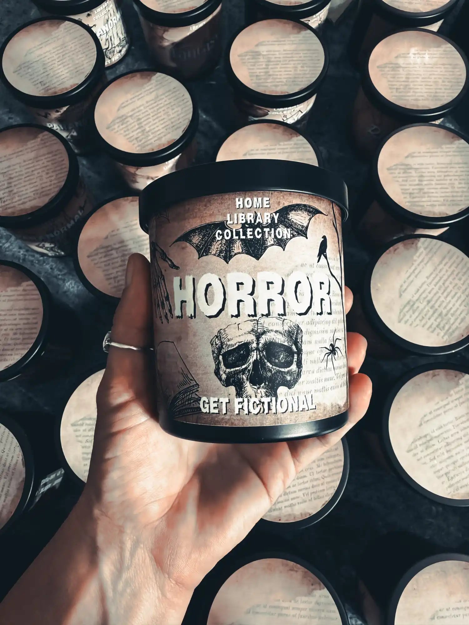 A candle in a black container with a spooky, vintage-style label featuring a skull and ’HORROR’ text.